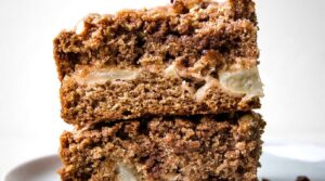 Ultra close-up macro cross-section of moist cinnamon apple crumb cake showing tender baked apple chunks, spiced cake crumb, and thick brown sugar pecan streusel