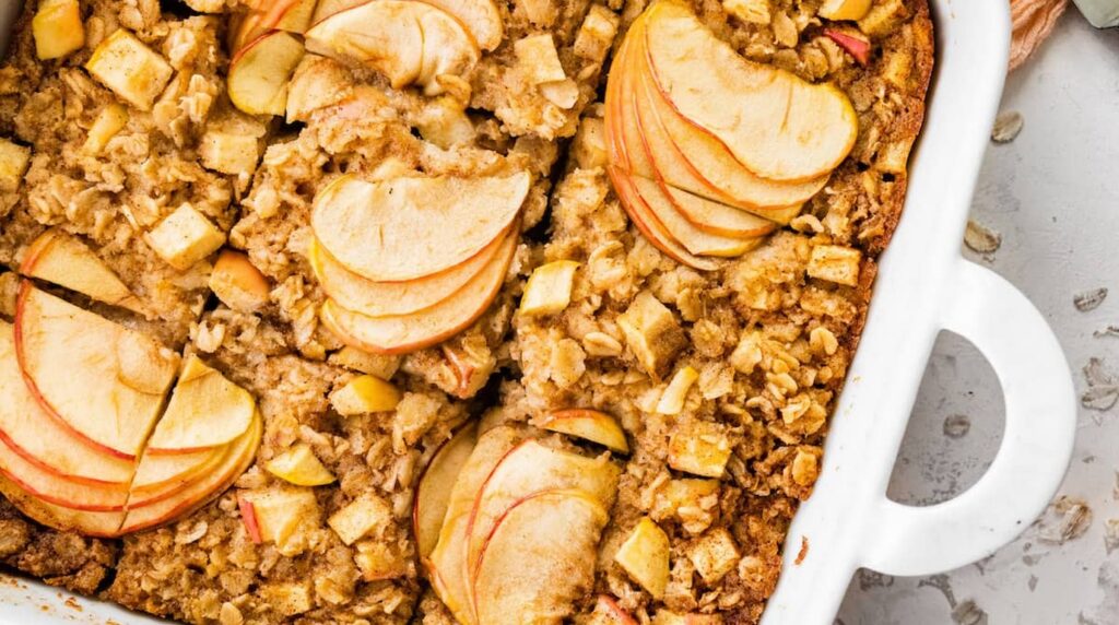 Ultra close-up macro of golden bubbling apple cinnamon baked oatmeal with toasted pecans in baking dish