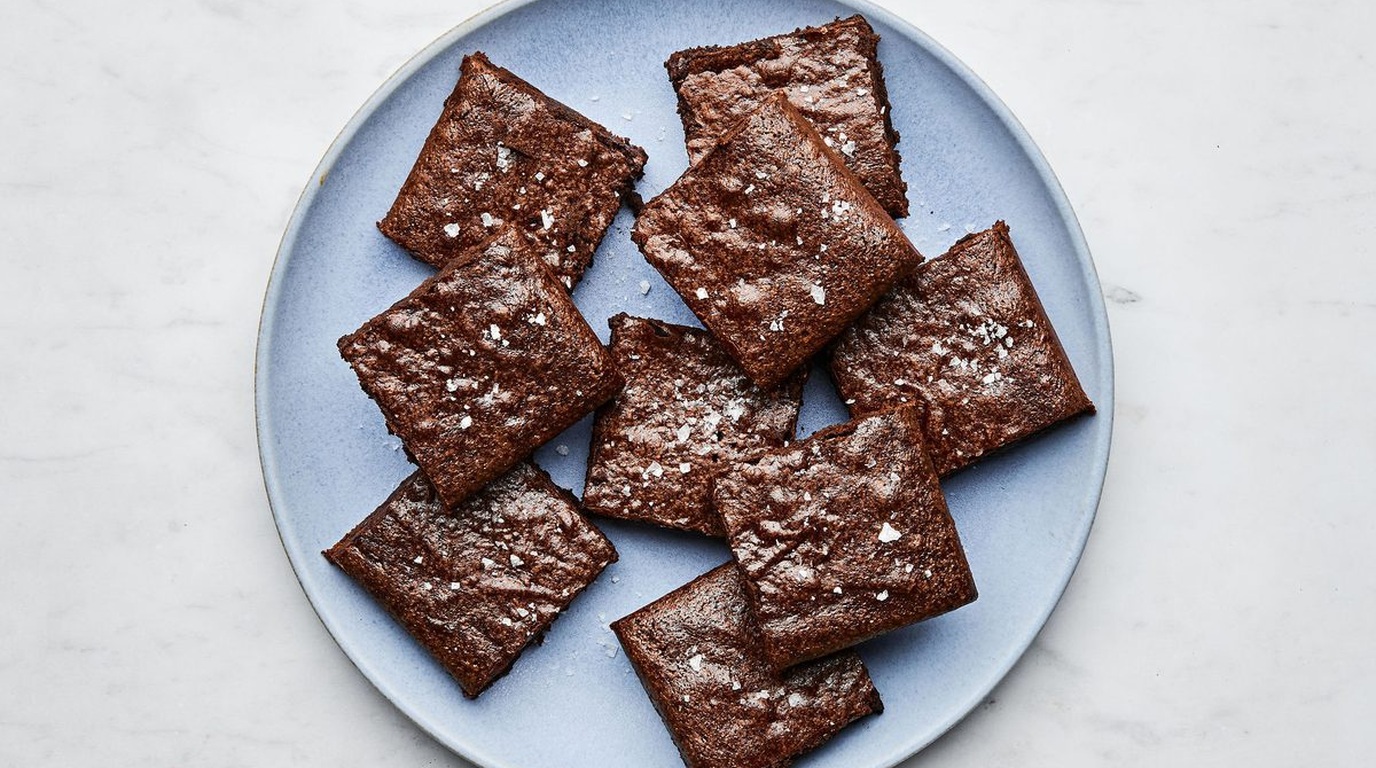 Ultra close-up macro of dense, fudgy chocolate brownies showing shiny crinkly papery top crust and melted dark chocolate pockets