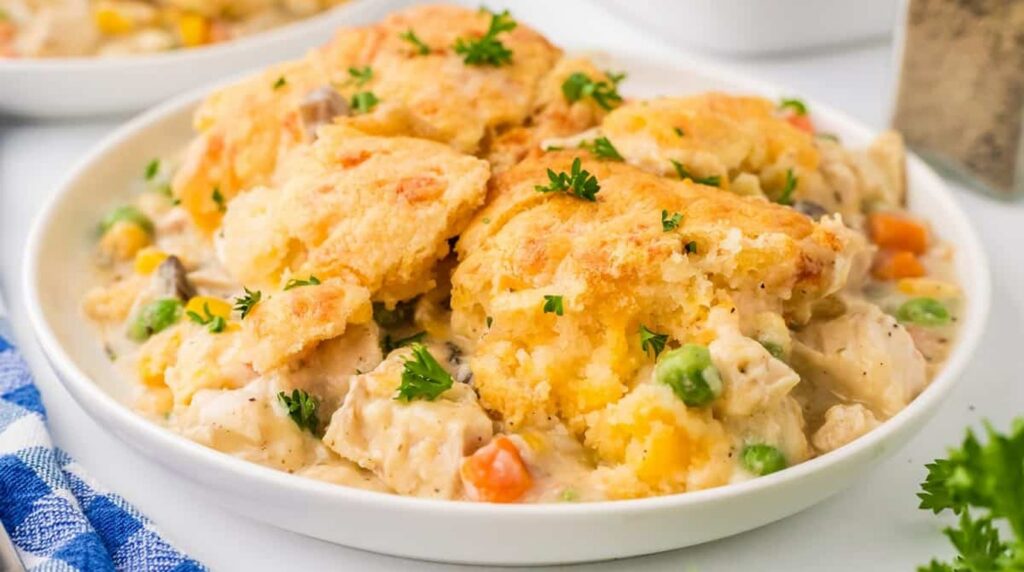 Ultra close-up macro of golden bubbling chicken cobbler casserole with garlic cheddar biscuit topping in baking dish