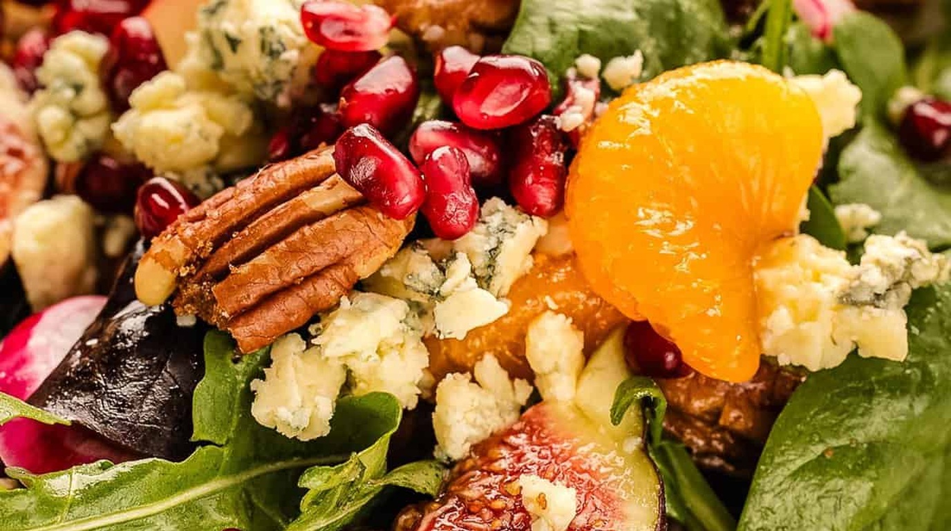 Ultra close-up macro of vibrant autumn harvest salad with crisp apples, candied pecans, cranberries, and crumbled feta