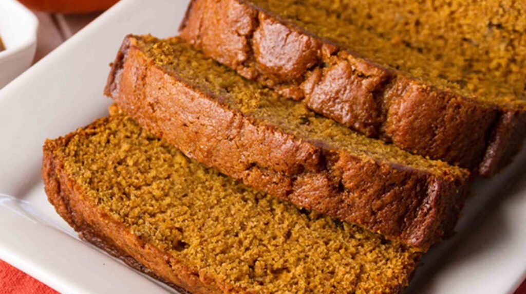 Ultra close-up macro of tender golden pumpkin bread slice showing moist spiced crumb and bakery crust