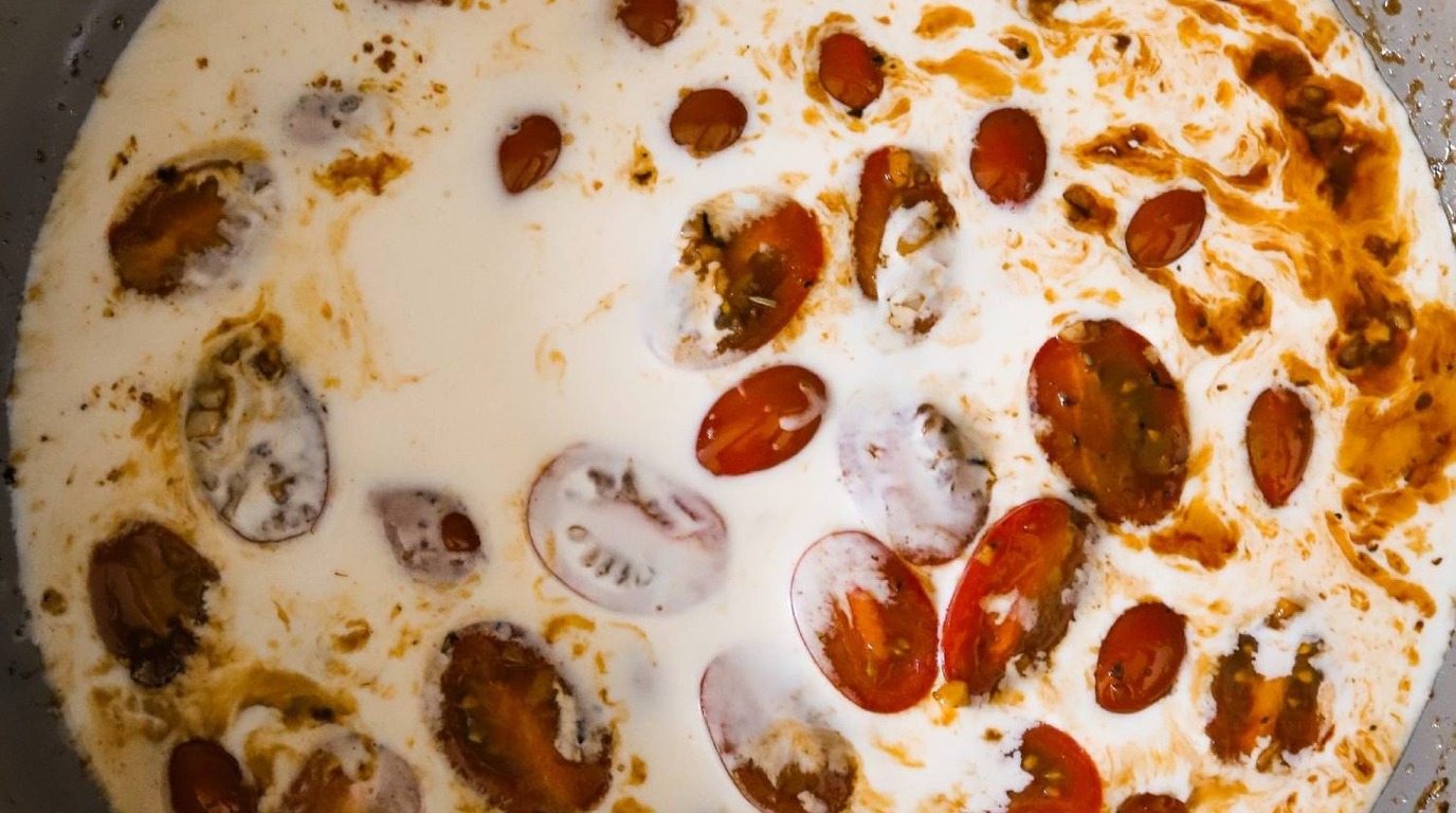 Ultra close-up macro of golden pan-seared chicken cutlets simmering in velvety garlic parmesan cream sauce with spinach and sun-dried tomatoes